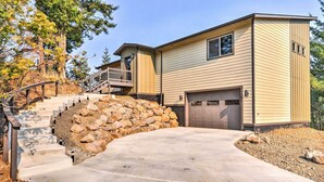 A two-story house with a stone retaining wall, a front garage, and a staircase leading to a balcony. - 'gorge Retreat' - Modern Carson Home w/ Mtn Views! (Carson)