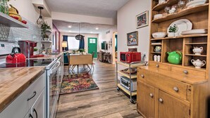 A kitchen with wooden cabinets, a microwave, and a red kettle.