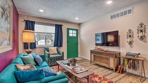A living room with a teal sofa, a coffee table, a TV, and a bookshelf.