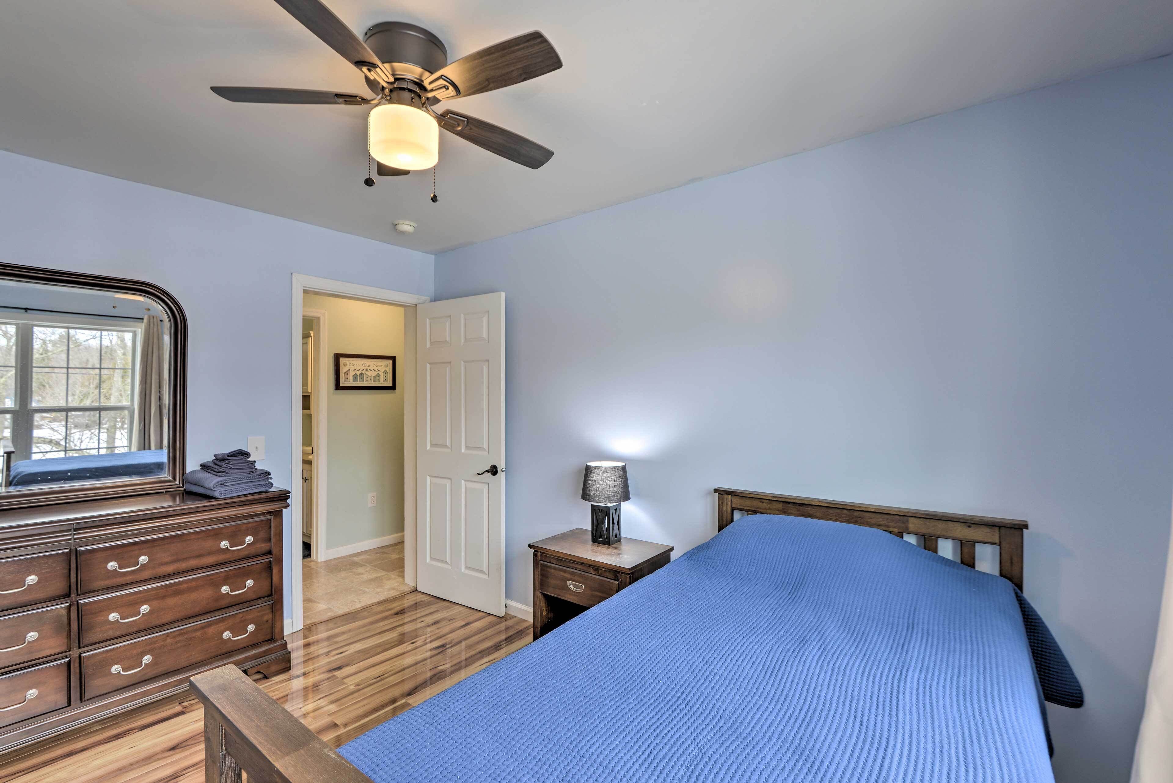 A bedroom with a bed, dresser, nightstand, and ceiling fan.