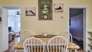 A dining area with a wooden table, white chairs, and a clock on the wall.