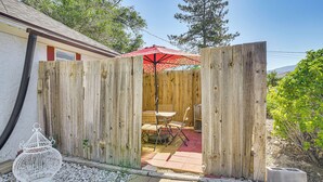 A wooden fence with a patio area, including a table and chairs, and a red umbrella.