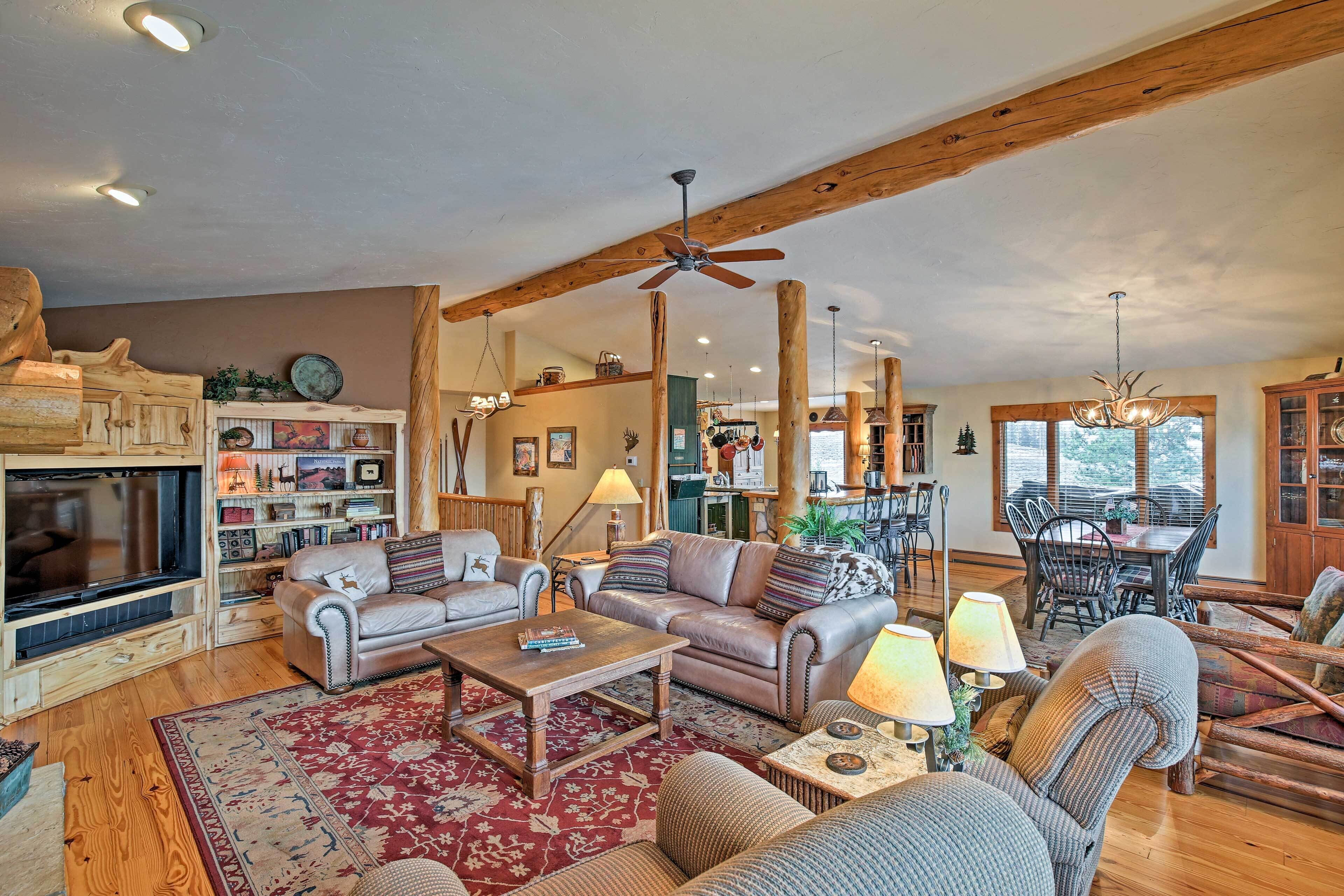 A spacious living room with a fireplace, leather sofa, wooden coffee table, and a dining area with a chandelier.
