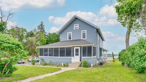 A two-story house with a porch, a screened-in front room, and a small front yard.