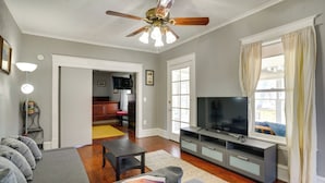 A living room with a sofa, TV, and ceiling fan.