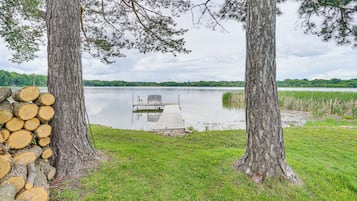 A dock extending into a calm lake, surrounded by trees and a grassy area.