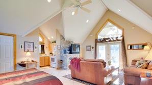 A spacious living area with a high ceiling, a fireplace, a television, and a large window. - Peaceful Lake Lure Cabin w/ Fireplace! (Lake Lure)