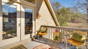 A covered porch with two chairs, a small table, and a decorative hanging. - Peaceful Lake Lure Cabin w/ Fireplace! (Lake Lure)