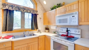 A kitchen with wooden cabinets, a microwave, an oven, and a sink. - Peaceful Lake Lure Cabin w/ Fireplace! (Lake Lure)