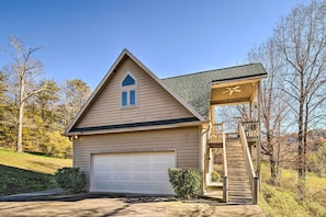 A single-story house with a garage, a small porch, and a staircase leading to a deck.