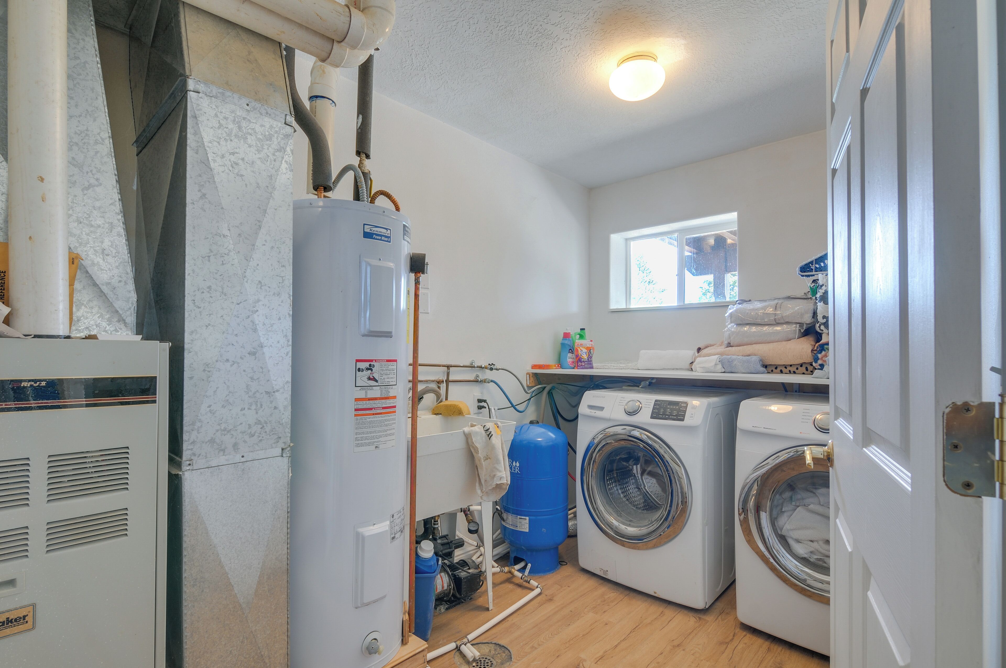 A laundry room with a water heater, washing machines, and a window with natural light.