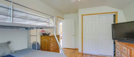 A bedroom with a bunk bed, a dresser, a television, and a ceiling fan.