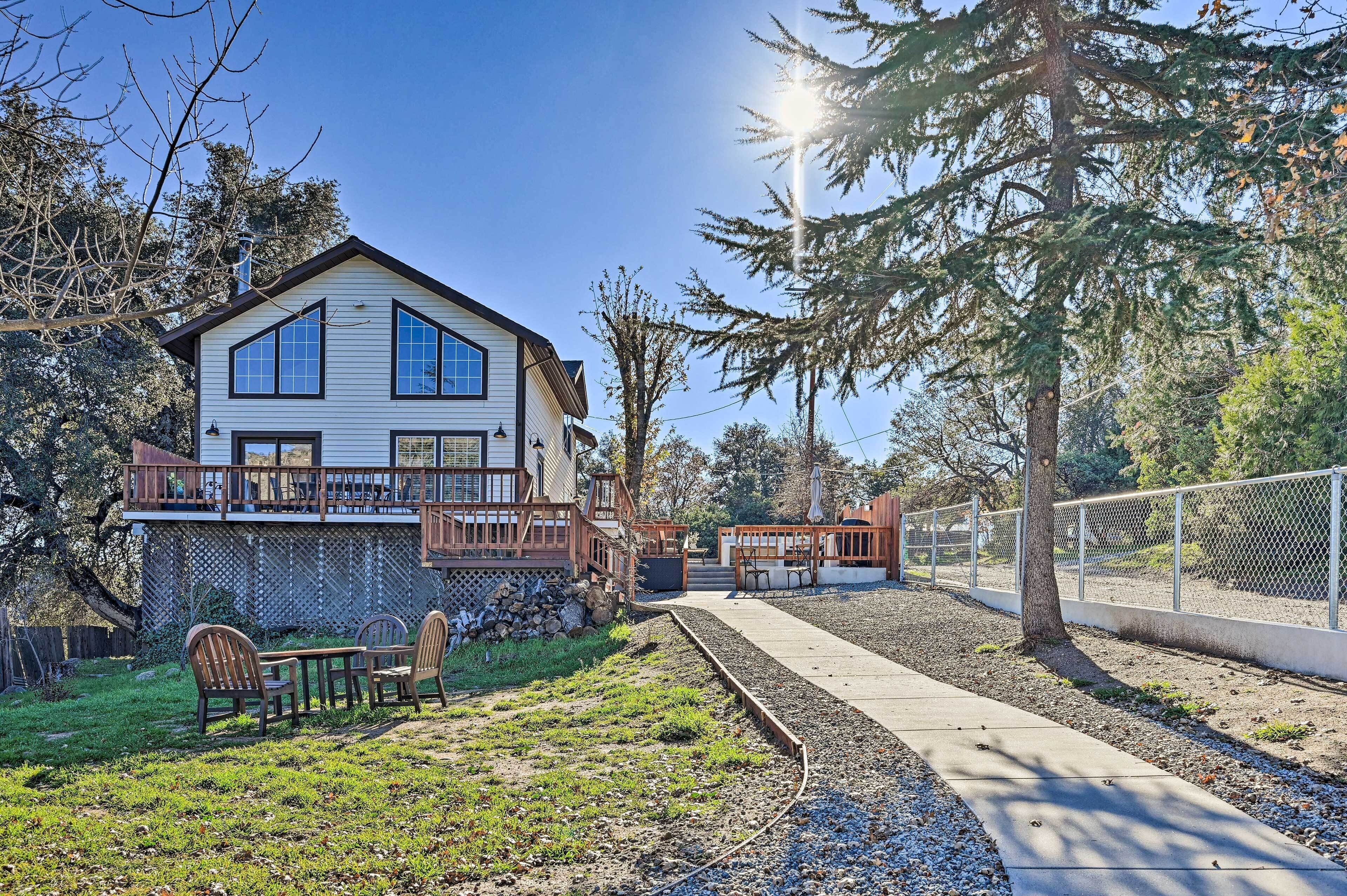 A two-story house with a deck, a patio, and a pathway leading to a fence.