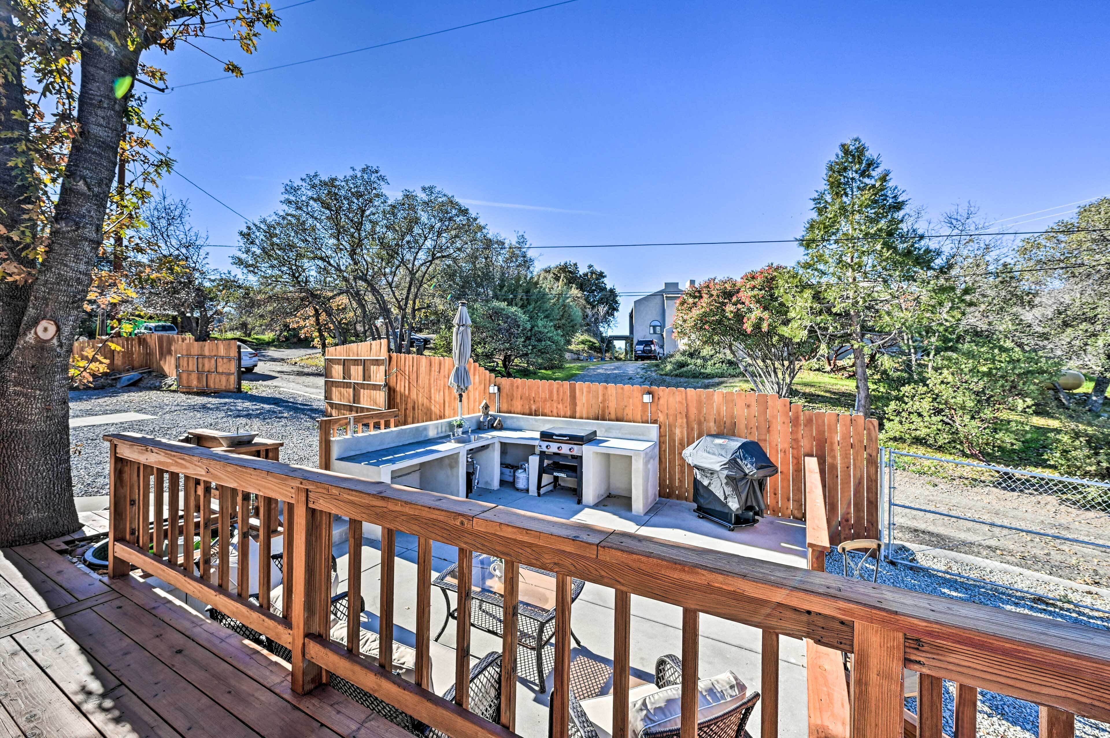 An outdoor kitchen area with a grill, seating, and a wooden deck.
