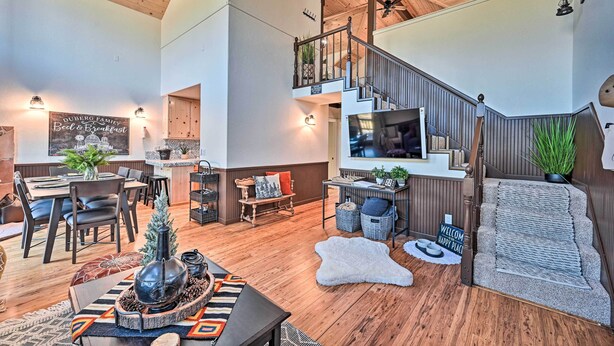 A spacious living area with a wooden staircase, a dining area, and a cozy seating space.