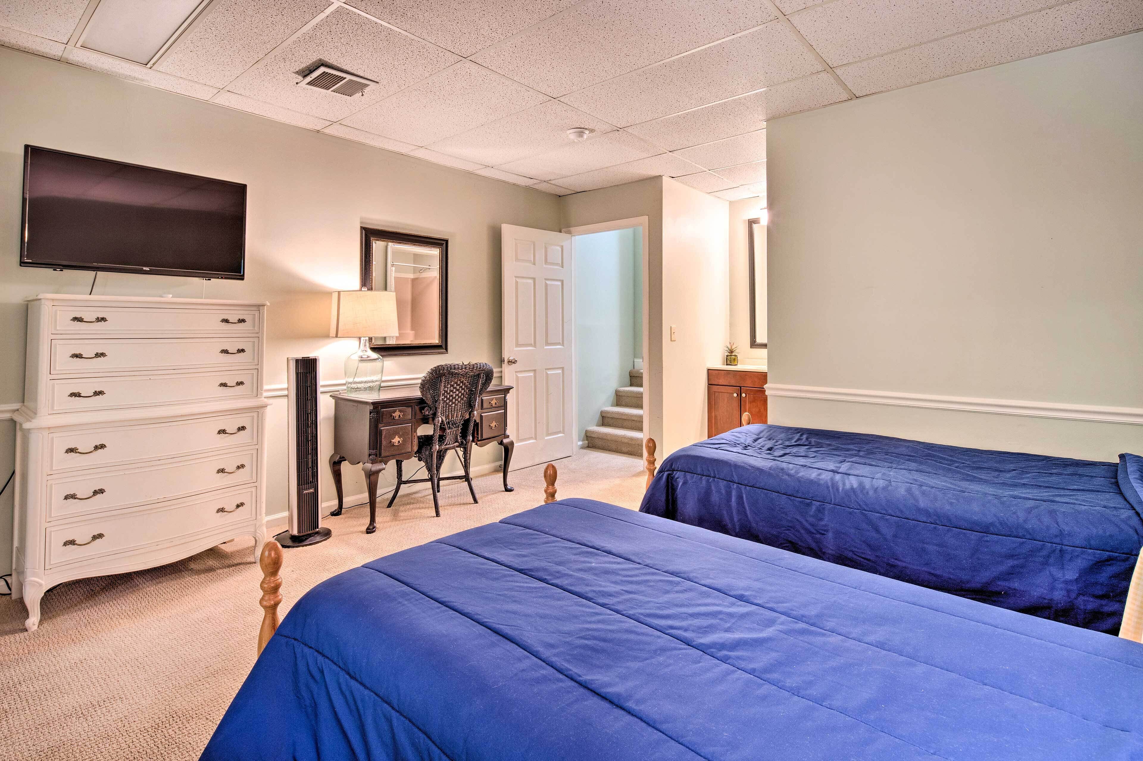 A bedroom with two beds, a desk, a dresser, and a TV.
