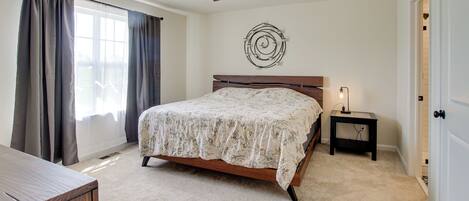 A bedroom with a bed, a ceiling fan, a bedside table with a lamp, and a door.