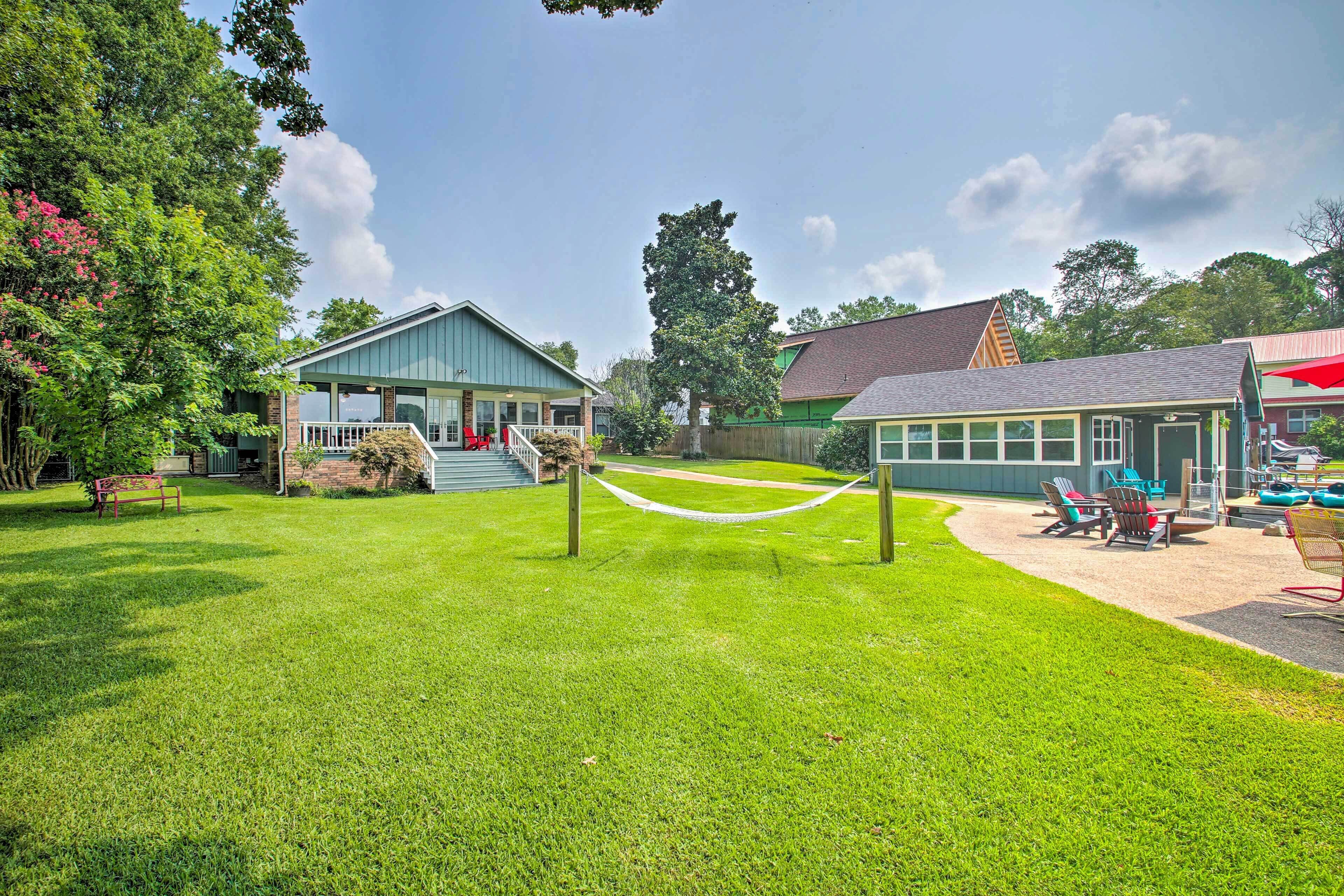A well-maintained grassy area with a hammock, a play area with chairs, and a building with a porch.