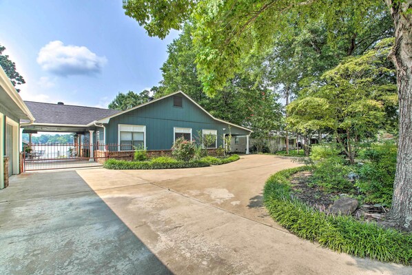 A residential house with a covered porch, a driveway, and a well-maintained garden with various plants and a large tree. - Kayaks & Dock: Lakefront Hot Springs Hideaway (Hot Springs)
