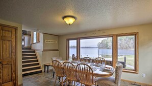 Un comedor con una mesa grande, sillas y vista a un lago.