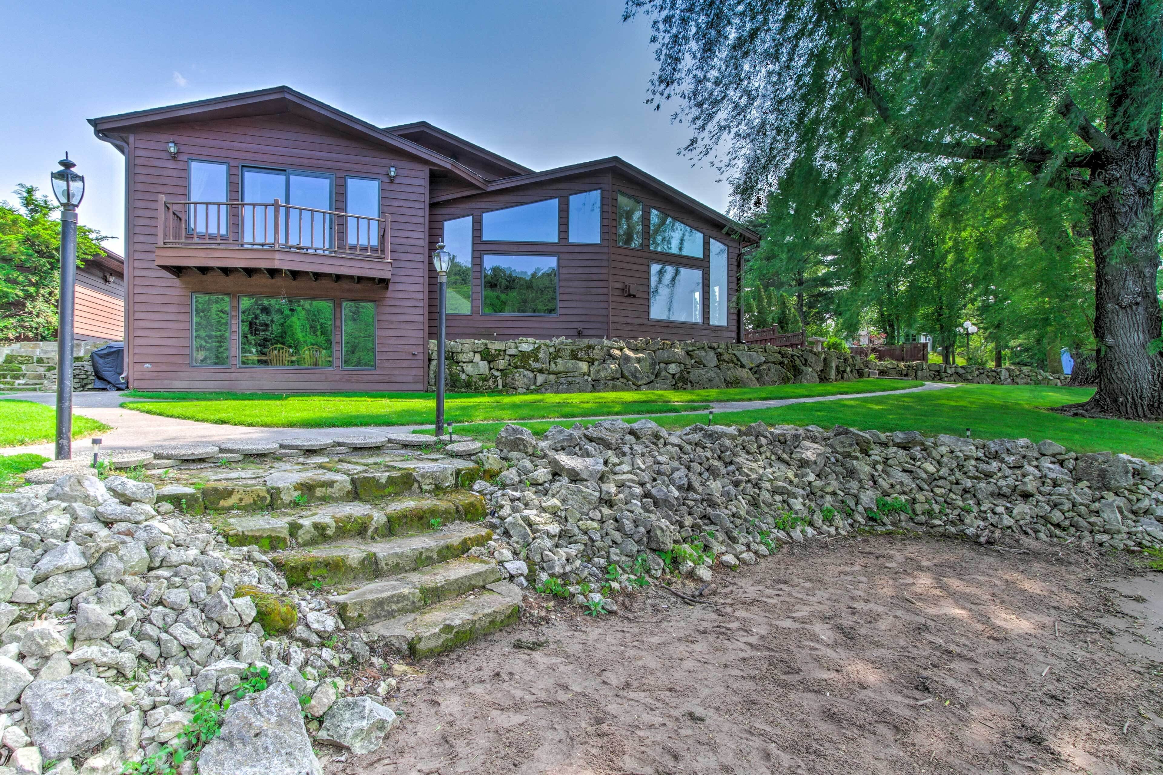 A two-story house with a balcony, stone steps, and a stone wall.