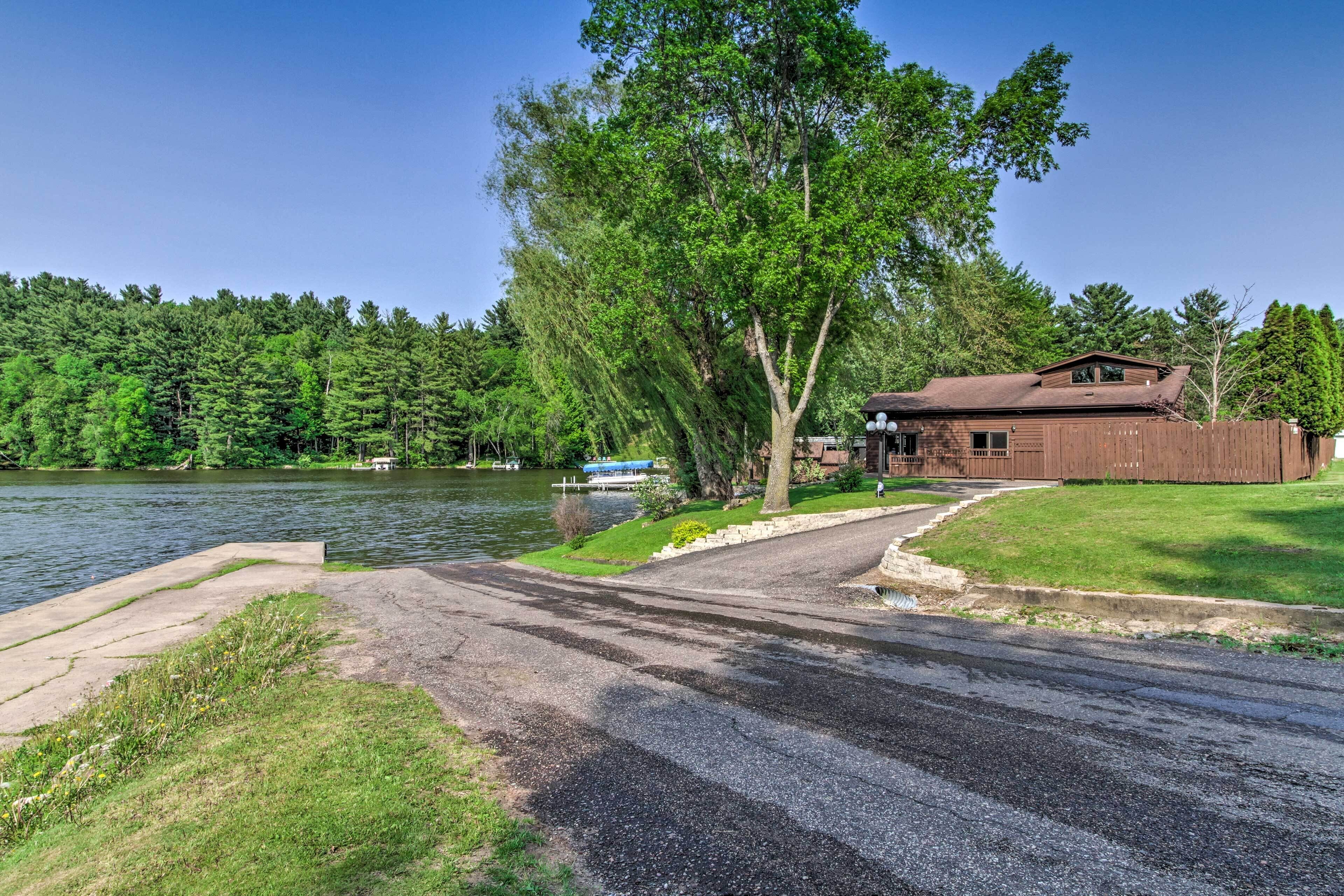 A lakeside property with a wooden cabin, a dock, and a grassy area.
