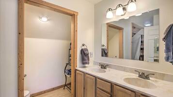 A bathroom with wooden cabinets, a large mirror, and two sinks.