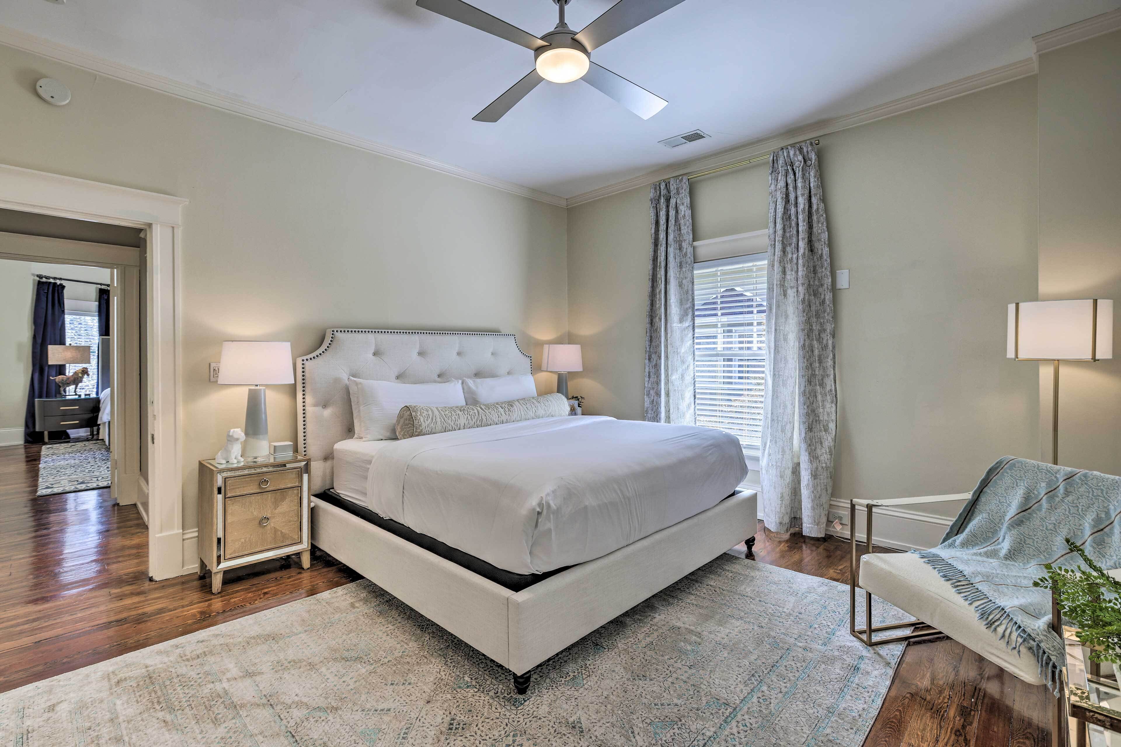 A bedroom with a bed, bedside lamps, a ceiling fan, and a chair with a blanket.