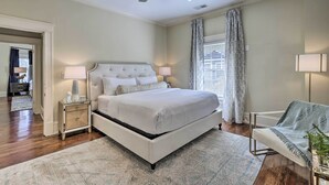 A bedroom with a bed, bedside lamps, a ceiling fan, and a chair with a blanket. - Immaculate Birmingham House w/ Covered Porch! (Birmingham)