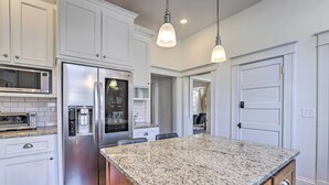 A kitchen with white cabinets, stainless steel appliances, granite countertops, and pendant lighting. - Immaculate Birmingham House w/ Covered Porch! (Birmingham)