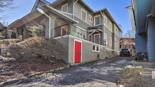 A two-story house with a red door, a balcony, and a driveway leading to a parked car. - Immaculate Birmingham House w/ Covered Porch! (Birmingham)