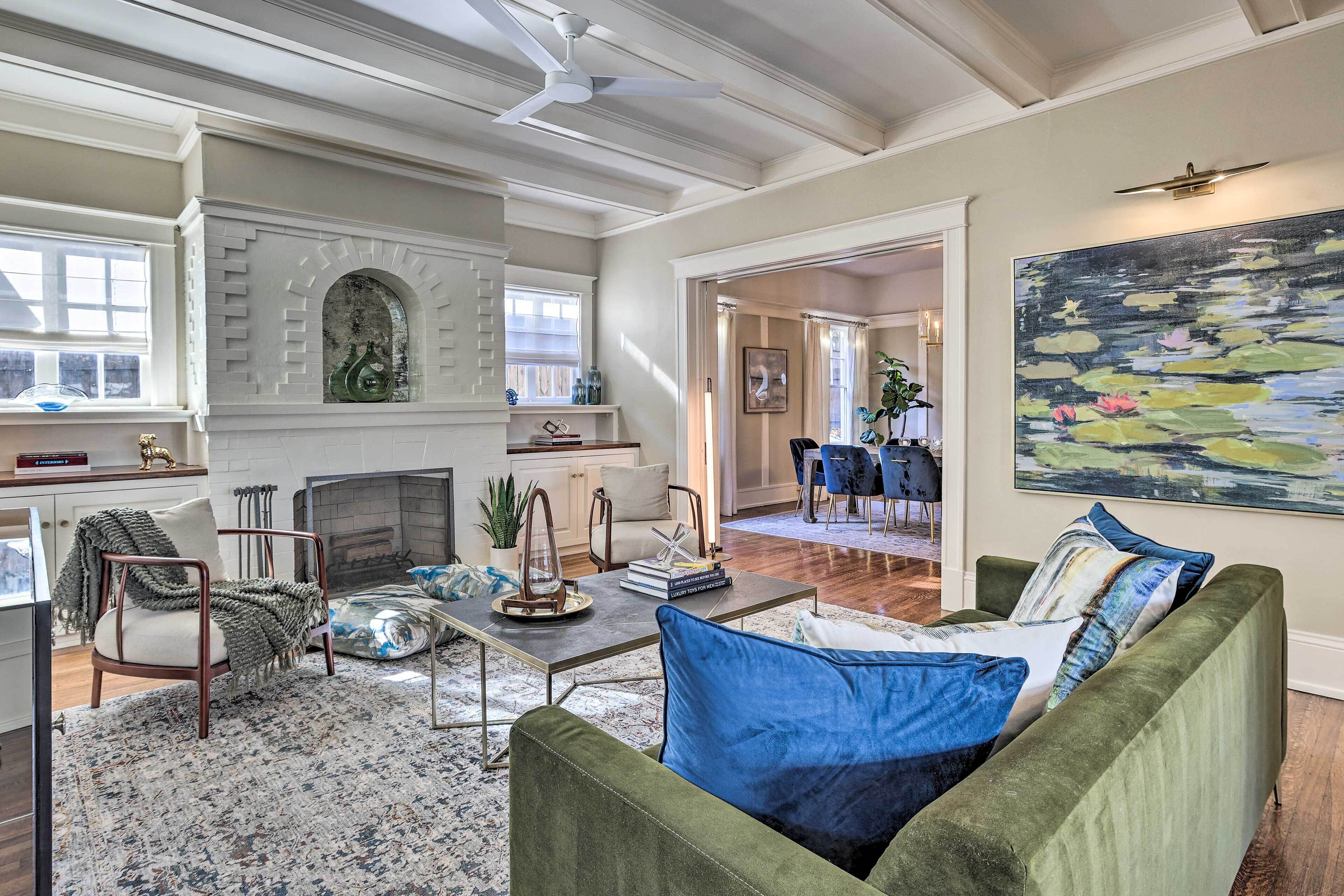 A spacious living room with a fireplace, green sofa, and a large painting.