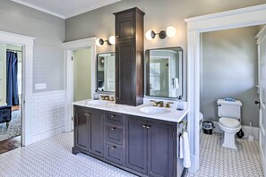 A bathroom with a dark vanity, two sinks, a large mirror, and a toilet. - Immaculate Birmingham House w/ Covered Porch! (Birmingham)