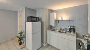 A compact kitchen with white cabinets, a built-in microwave, a refrigerator, a sink, and a coffee maker. - 'loretta' Sun-kissed Apt on Country Music Hwy (Hagerhill)
