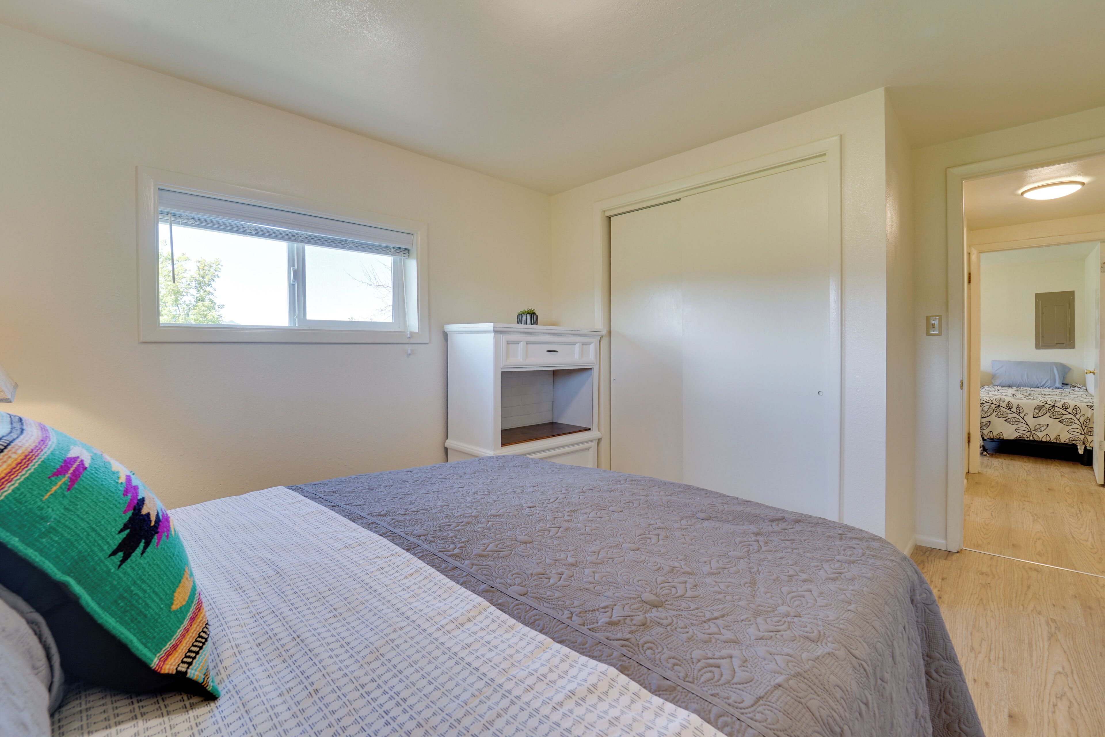 Un dormitorio con cama, ventana, armario y puerta que da a otra habitación.
