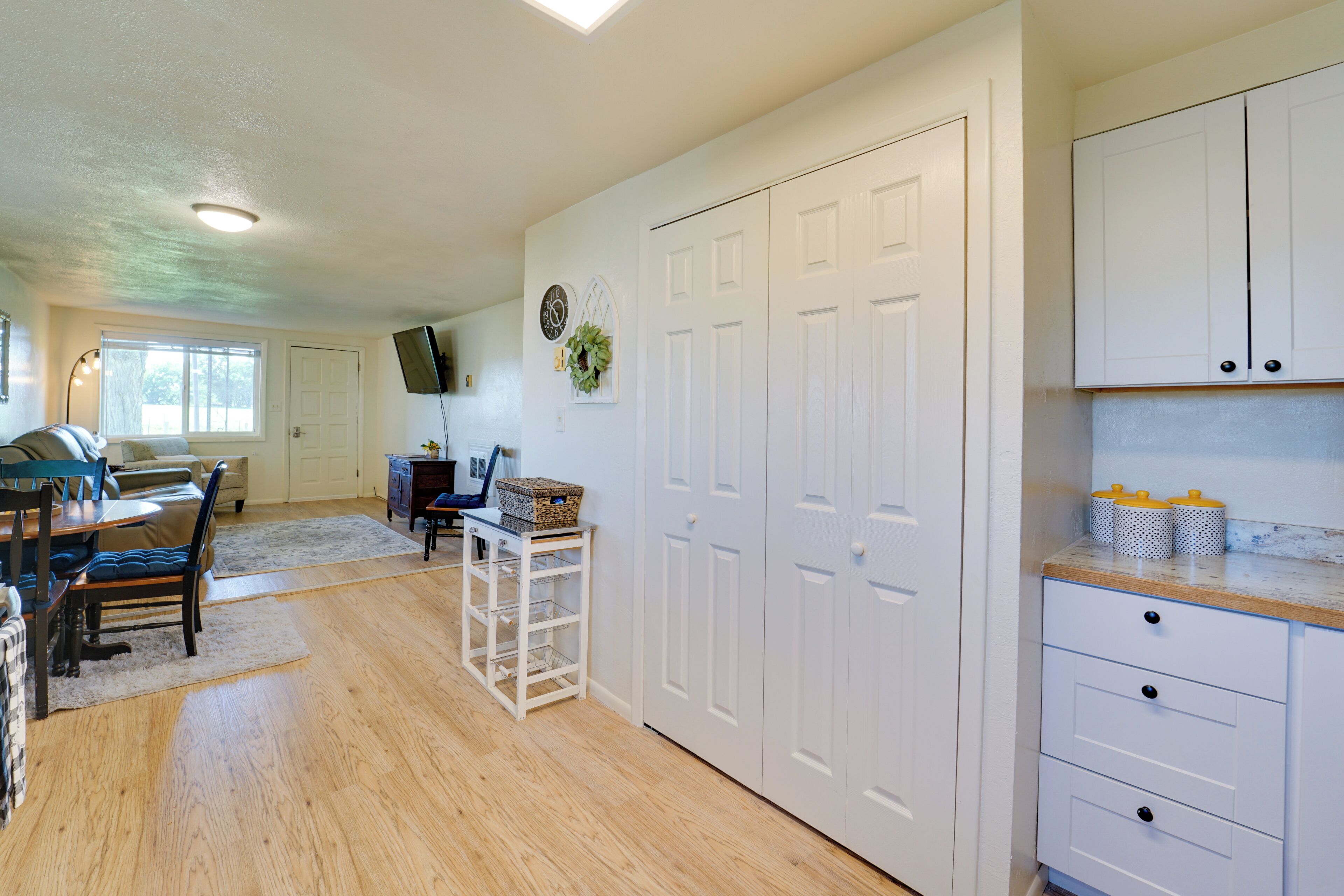Una cocina amplia con armarios blancos, encimera de madera y zona de comedor con mesa y sillas.