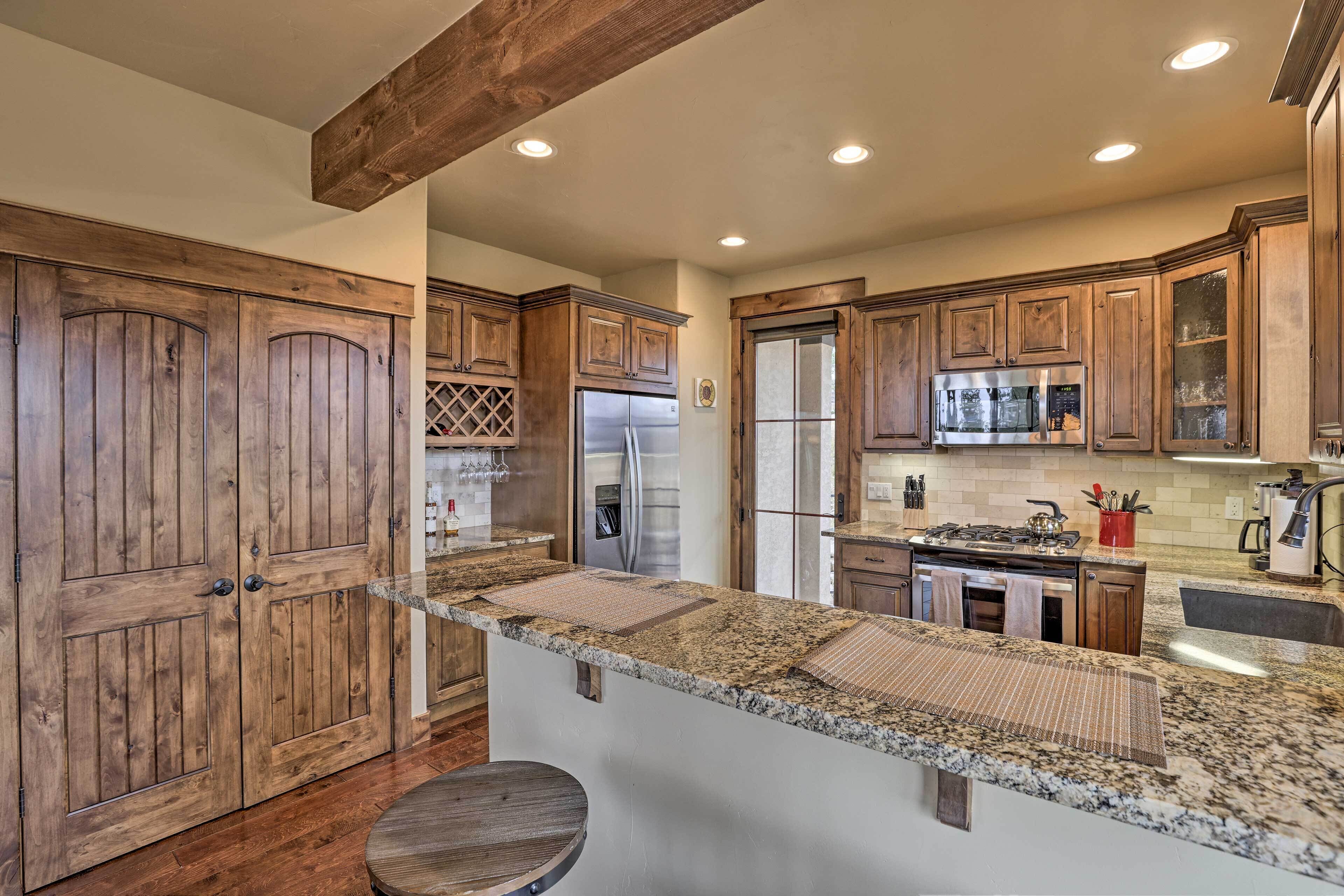 A kitchen with wooden cabinets, granite countertops, a stainless steel refrigerator, and a built-in oven.