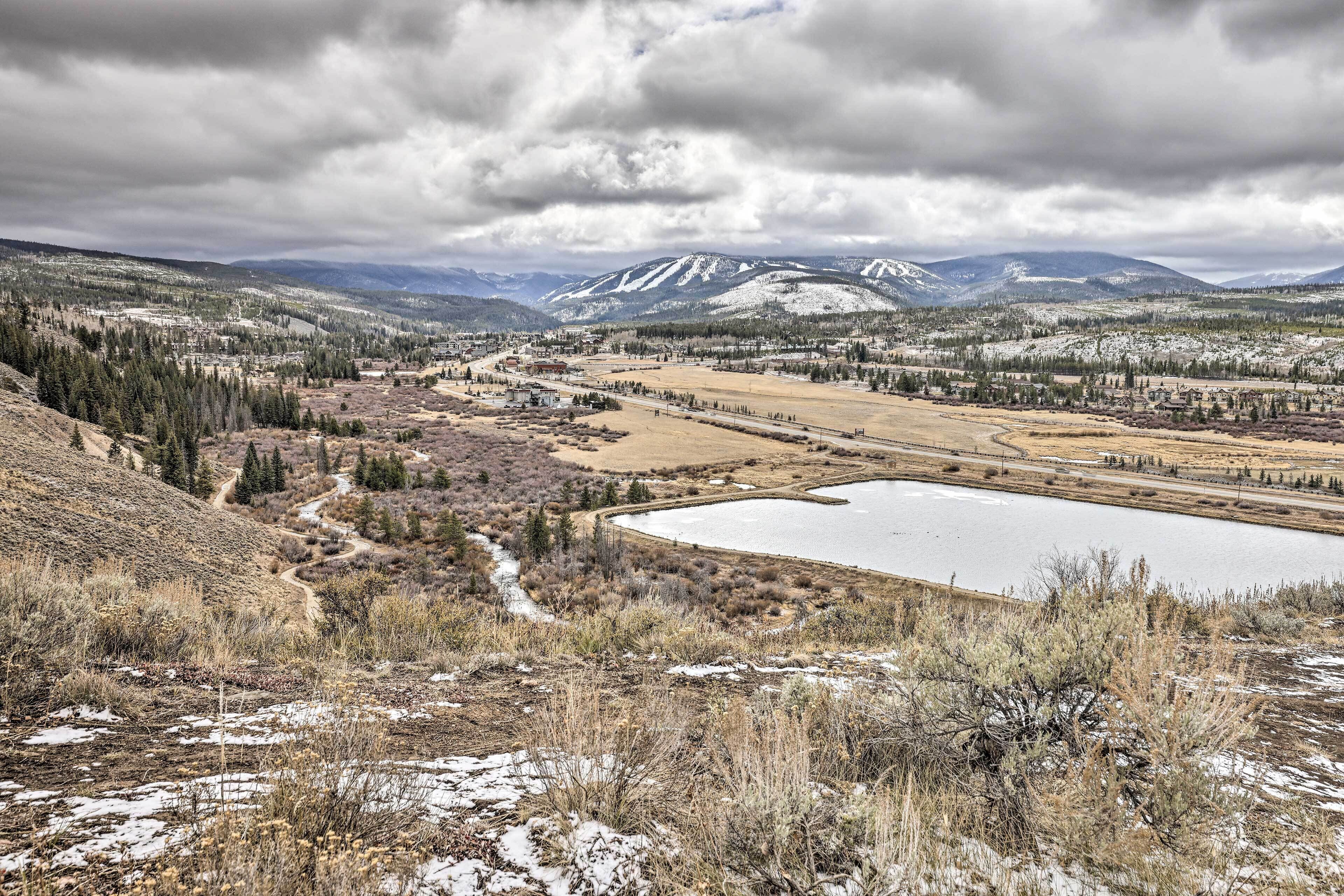 Un paysage montagneux avec un lac, des zones boisées et un petit village.