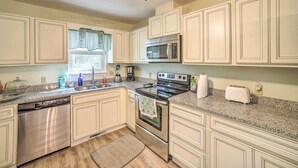 A kitchen with white cabinets, stainless steel appliances, and a granite countertop. - Oak Island Home w/ Yard < 1 Mi to the Beach! (Oak Island)