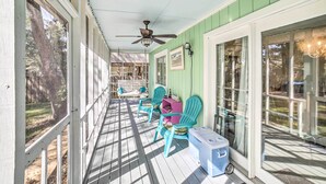 A covered porch with teal chairs, a cooler, and a ceiling fan. - Oak Island Home w/ Yard < 1 Mi to the Beach! (Oak Island)