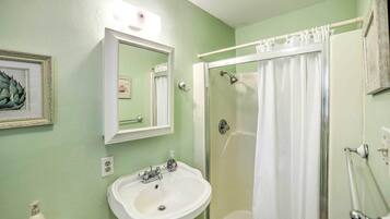 Une salle de bain avec un lavabo, un miroir, une douche et un tableau encadré au mur.