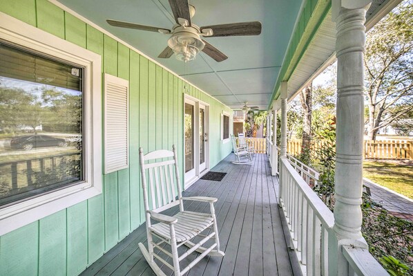 Eine Veranda mit Schaukelstuhl, Deckenventilator und Blick auf den Garten.