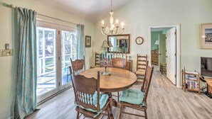 A dining area with a round wooden table, six chairs, and a chandelier. - Oak Island Home w/ Yard < 1 Mi to the Beach! (Oak Island)