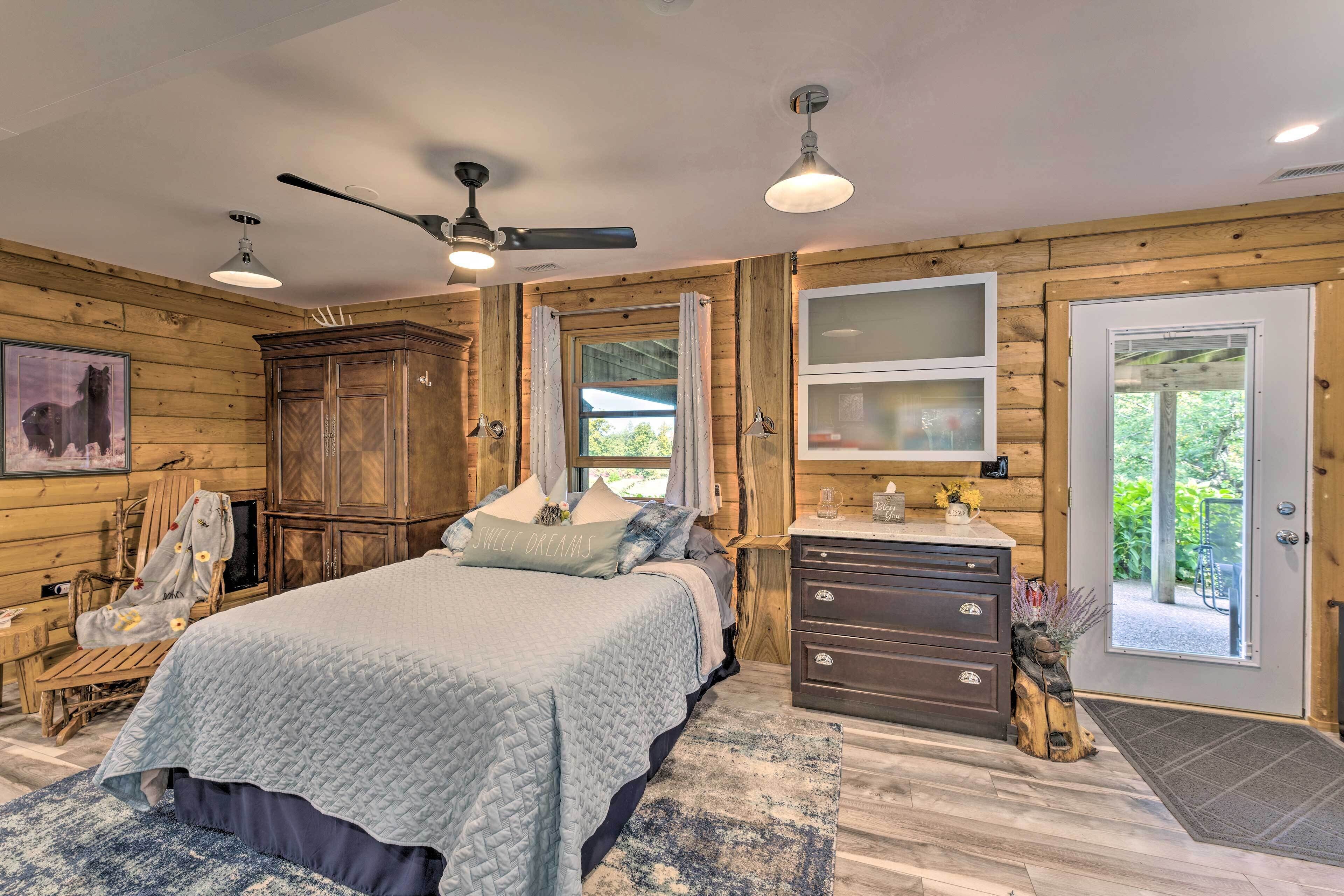 A cozy bedroom with a bed, wooden walls, a ceiling fan, and a dresser.