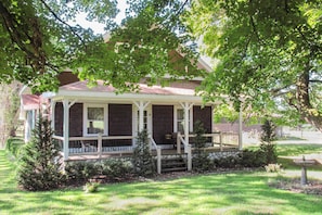 A two-story house with a porch, a small front yard, and a bird feeder. - Wilderness Retreat & Cross-country Ski Center! (Le Roy)