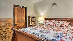 Een slaapkamer met een houten bed, een dressoir, een boekenkast en een lamp.
