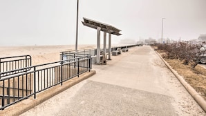 A pathway with a metal railing, a lamp post, and a concrete structure. - No-frills Hampton Cottage - Steps to Beach! (Hampton)