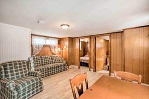 A cozy room with a wooden floor, a checkered sofa set, a wooden dining table, and a wooden wardrobe. - No-frills Hampton Cottage - Steps to Beach! (Hampton)