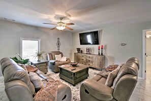 A living room with leather sofas, a wooden coffee table, a ceiling fan, and a flat-screen TV.