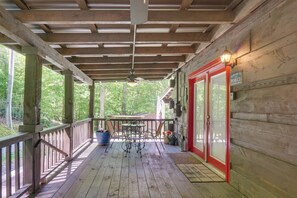 A wooden deck with a railing, a table with chairs, and a door with a sign.